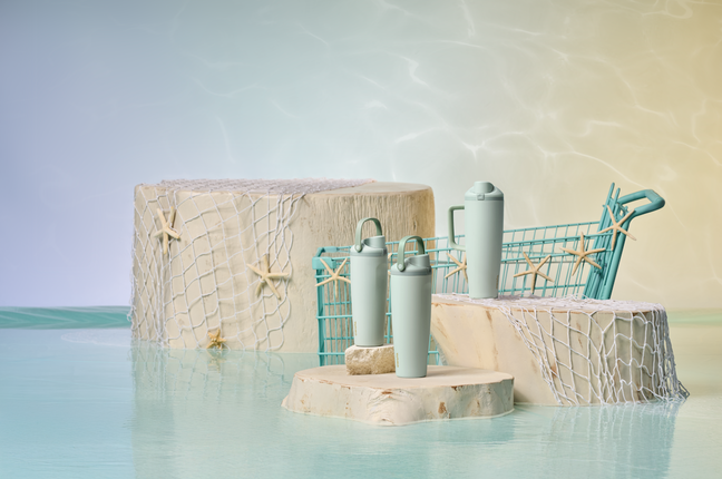 Three teal bottles on sandy pillars surrounded by ocean themed elements